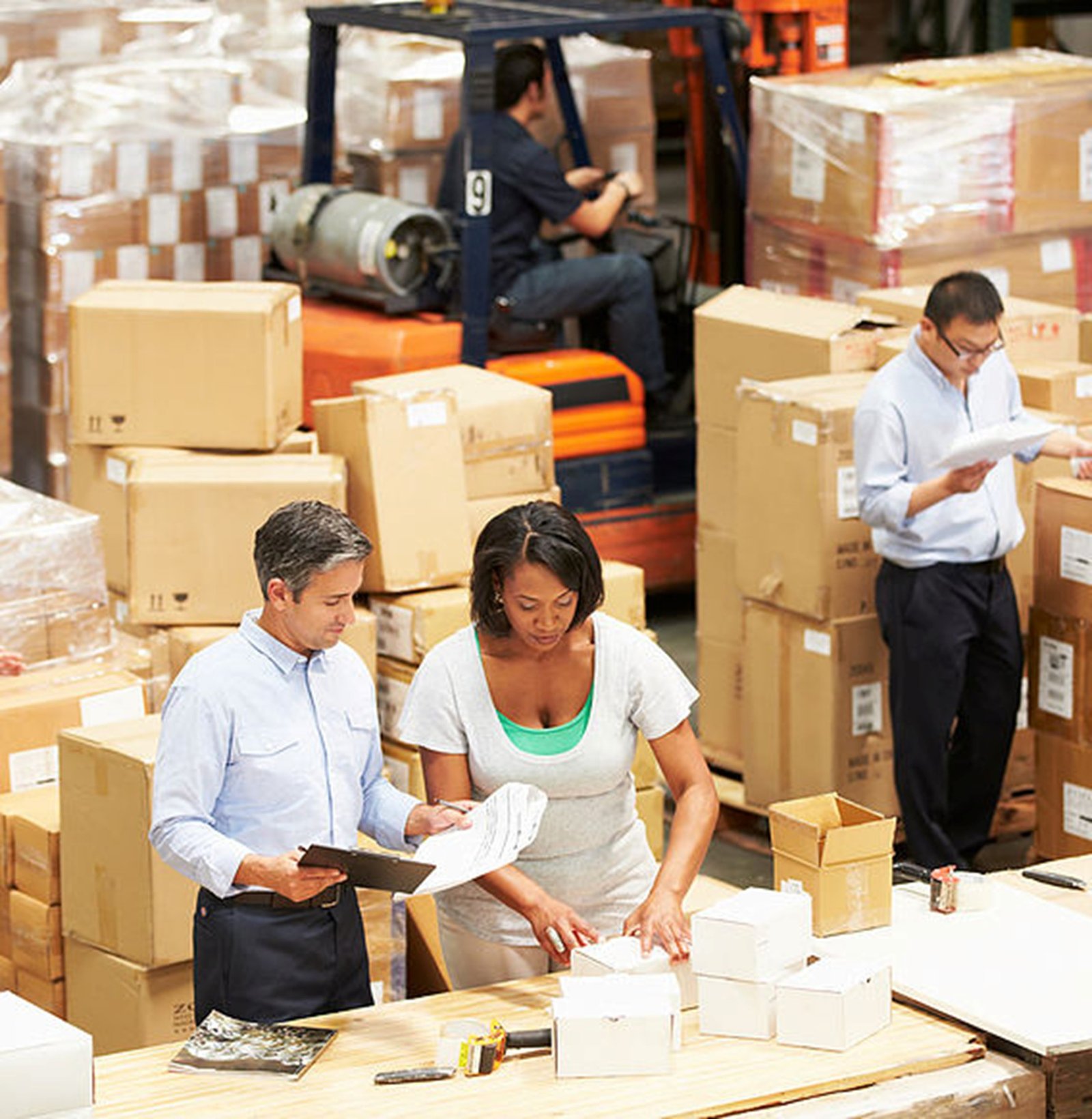 Workers organizing and inspecting packages in a busy warehouse.