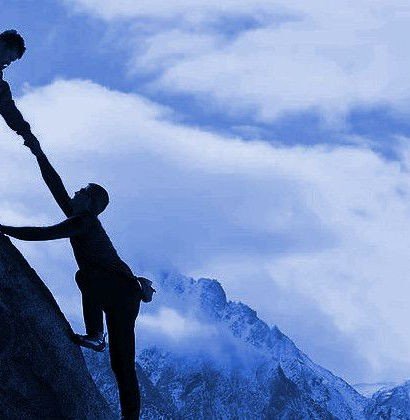 Two climbers helping each other on a snowy mountain peak.